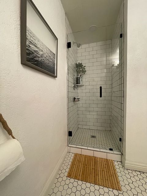 The shower features crisp white subway tile, with a honeycomb floor.