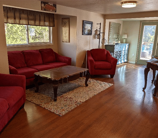 Living area with couch nook, loveseat, chair and entrance to the deck in the distance.