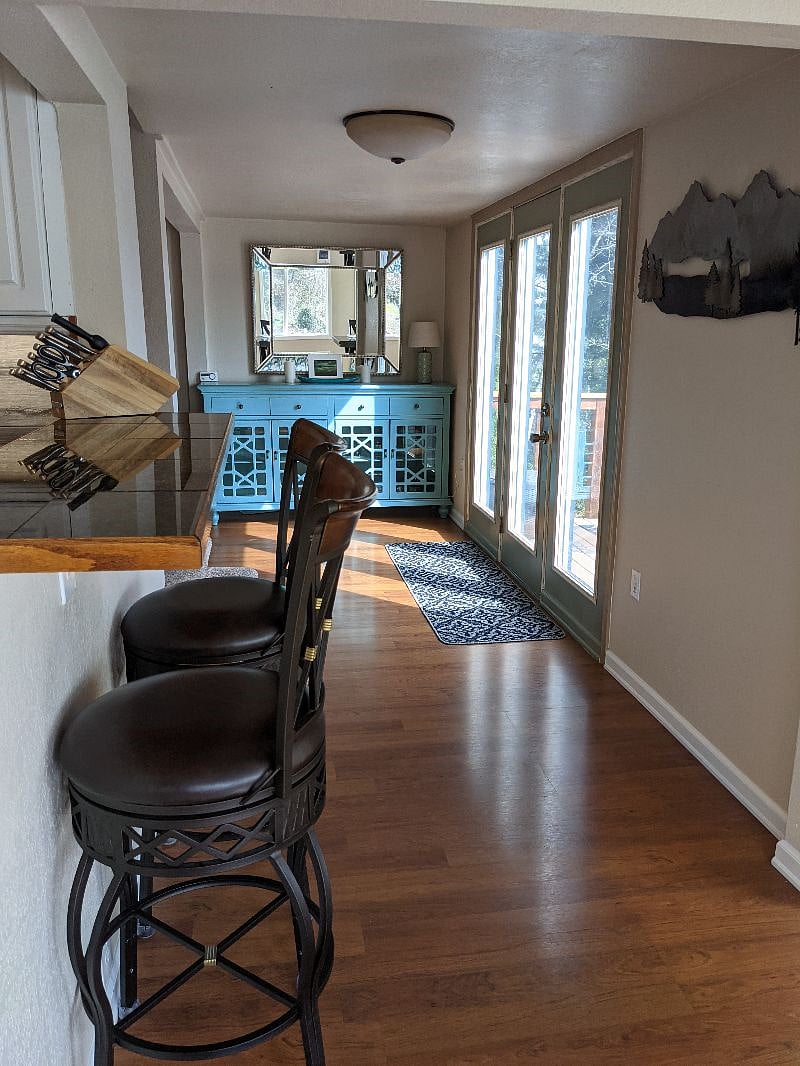 Looking past the bar seating area to aqua storage cabinet in the distance, stairs leading to upstairs on the left and door leading to deck on the right.