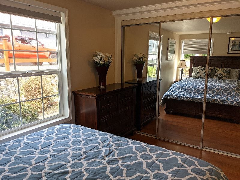 Another view of the Primary bedroom looking from headboard back to mirrored closet and matching Costco dresser