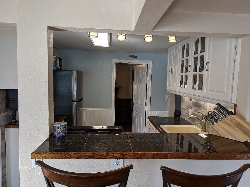 Bar overlooking the kitchen, with primary bedroom door in the distance.