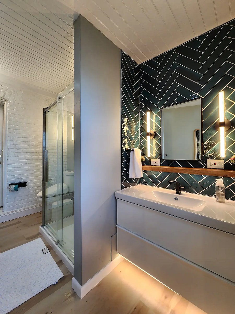 Stunning vanity setup with ocean green herringbone backsplash, warm led lighting.