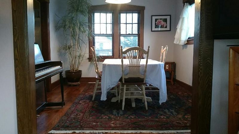 Dining room with seating for 8 and a piano.