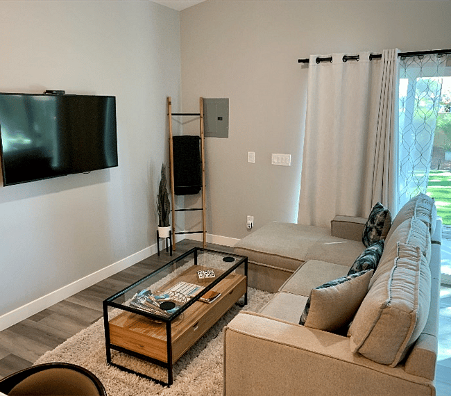 Living room with flat screen TV, pull out couch, coffee table with storage, blanket.