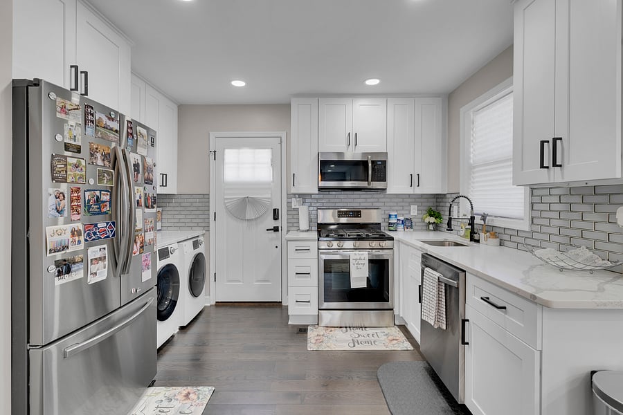 Stunning all-white chef's kitchen featuring sleek black accents, premium stainless steel appliances, and elegant quartz countertops.