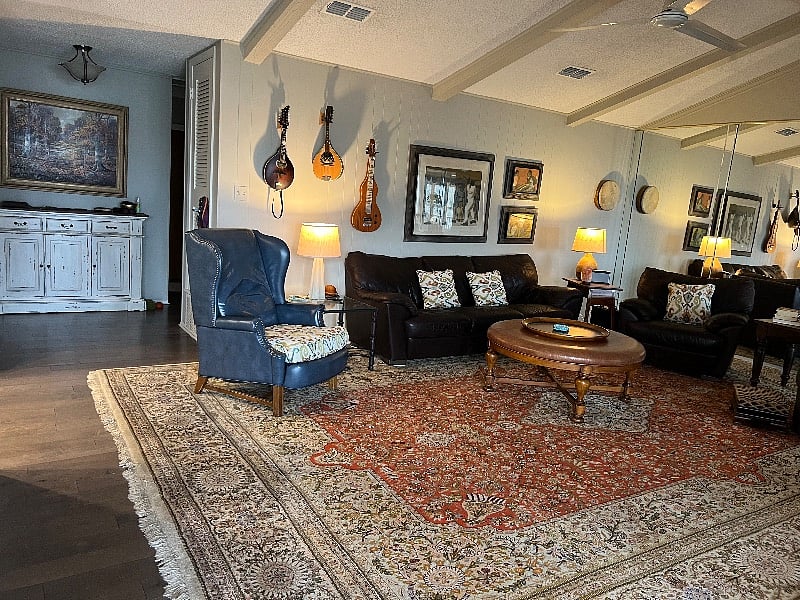 Very large living room. Mandolin and lap steel guitar on the wall.