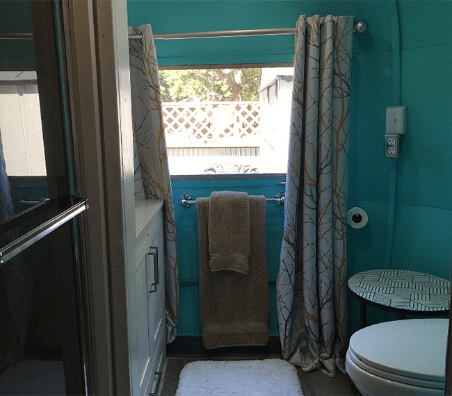 Fully remodeled bathroom in rear of Airstream with a standard shower, vanity, and a fully plumbed standard toilet 