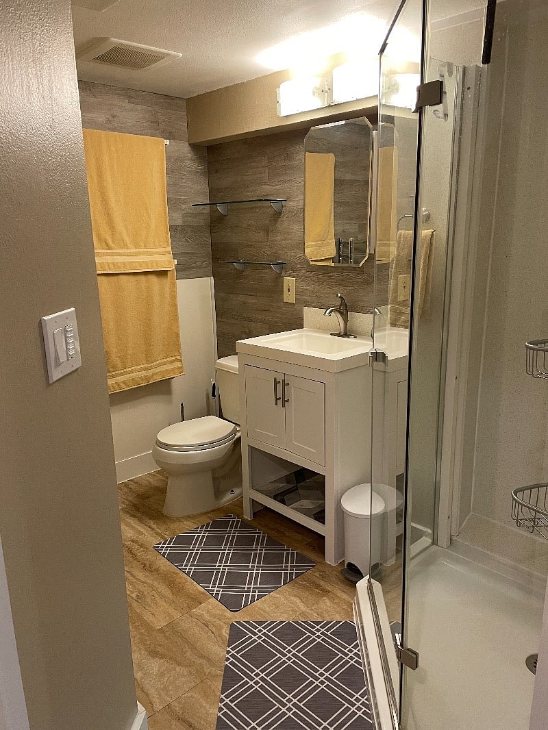 Private bathroom has glass shelves and modern vanity.