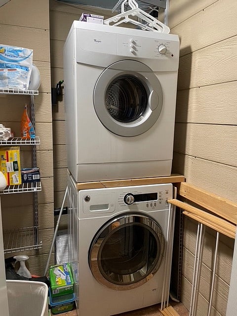 Stacked washer and dryer are compact in size. Laundry area has additional storage.