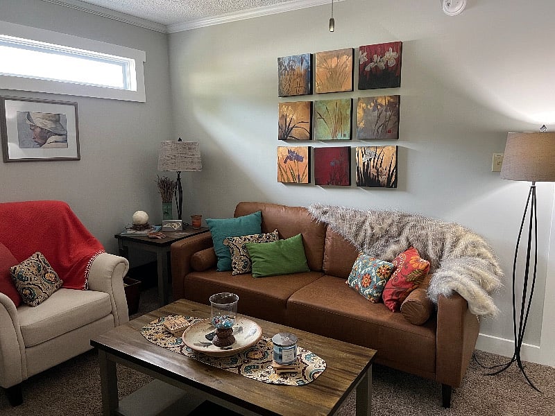 Sitting area with sofa, chair, electric fireplace and 60 inch Roku TV equipped for guest streaming password access. 