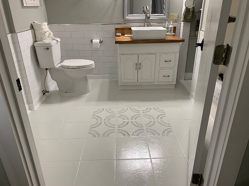The large bathroom contains a vessel sink, shower over deep tub, and open shelving to the right of the vanity. Lots of bright light in this bathroom. 