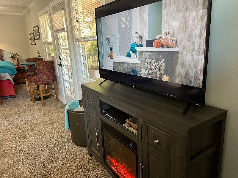 Between the tv and the bistro table and chairs is the second private entrance into the studio. The glass door, together with large windows, overlook the covered porch and back yard, bringing soft light into the space. 