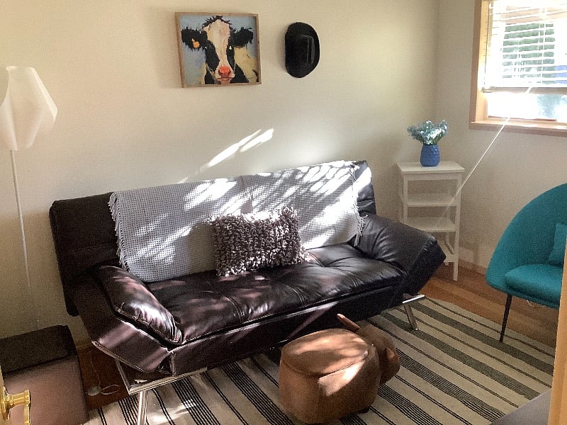 Second room in rental suite for lounge with wall mount smart TV and large closet with mirrored doors. This room can also serve as a bedroom for guests. It has pillows and bedding stored in a wooden chest in the room. 