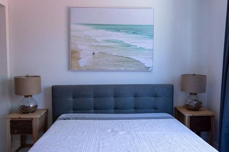 Bedroom with a queen sized bed, 2 night stands and lamps. Plenty of natural light from the large window.
