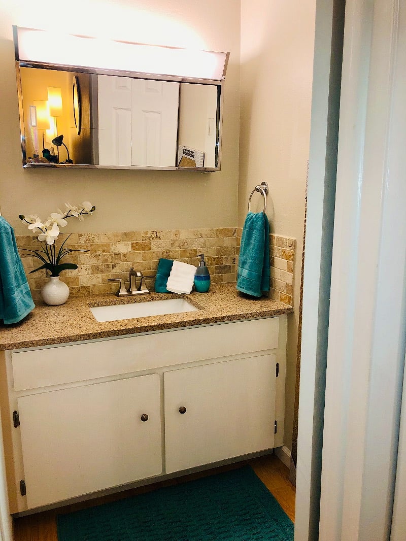 Separate room with retro lighted mirrored medicine cabinet, sink and storage outside bathroom makes it easy for two to get ready at same time.
