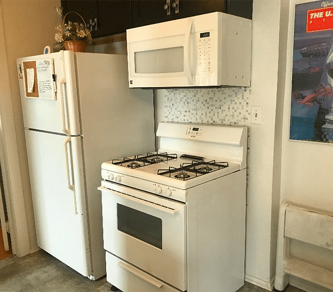 The kitchen is small but it has a full-sized refrigerator, a gas stove, a microwave, a dishwasher, a sink and a small meal-prep area.