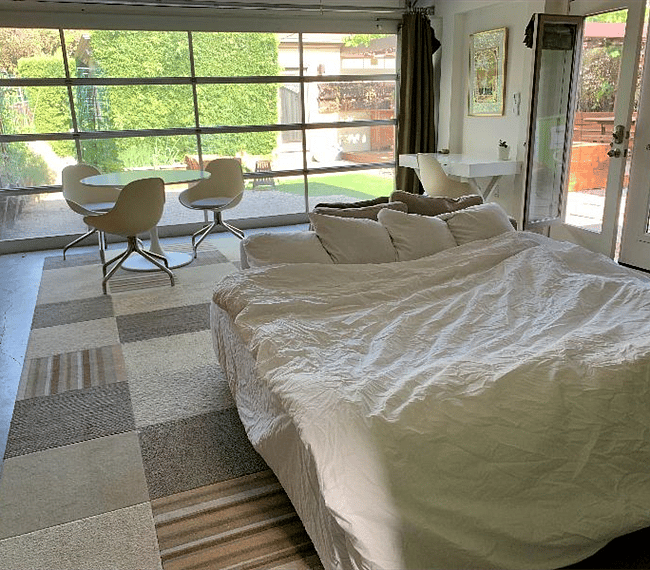 This configuration has a queen bed with ottoman seating behind. There is a dining table and a desk and four swivel chairs.