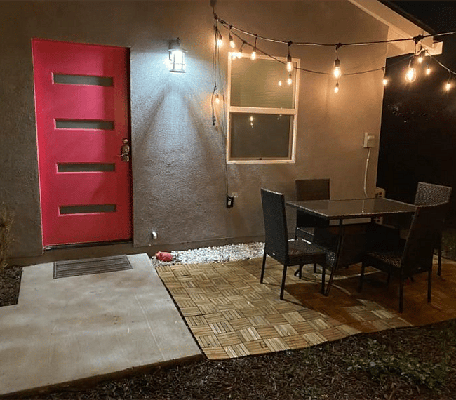 Front door with outdoor patio with chillout area and string lighting.