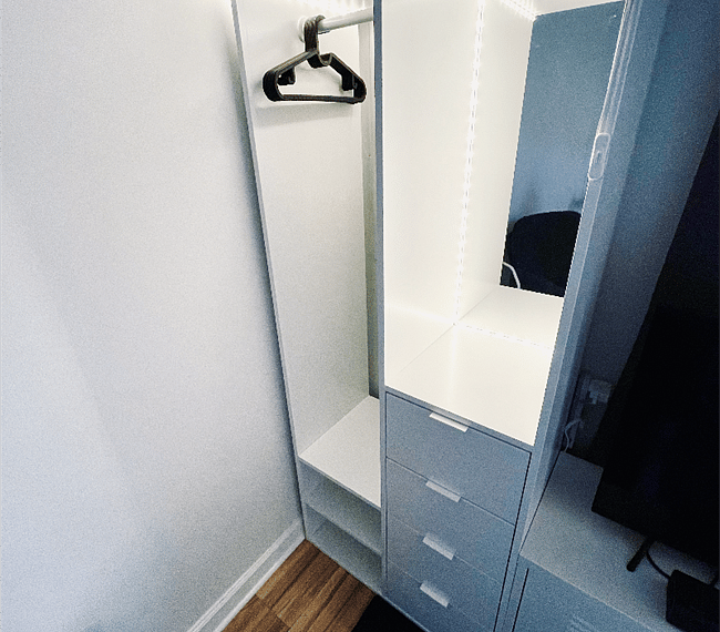 Open wardrobe unit with deep drawers, mirror, and lights.