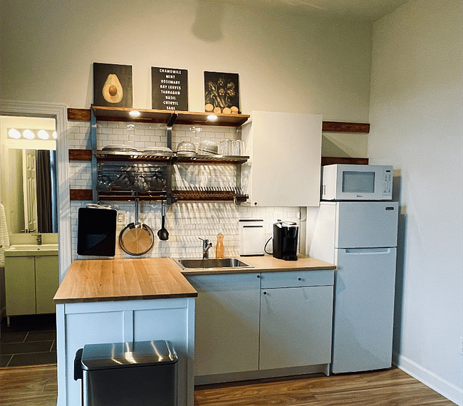 Fully-stocked kitchenette with pots, pans, electric hotplate, coffee maker, and microwave. Two-door refrigerator and cabinets allow for ample storage.