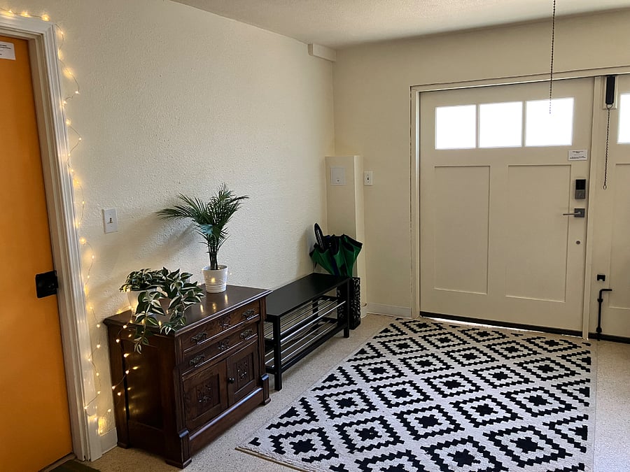 Entryway / mudroom with shoe bench. Orange door leads into studio.