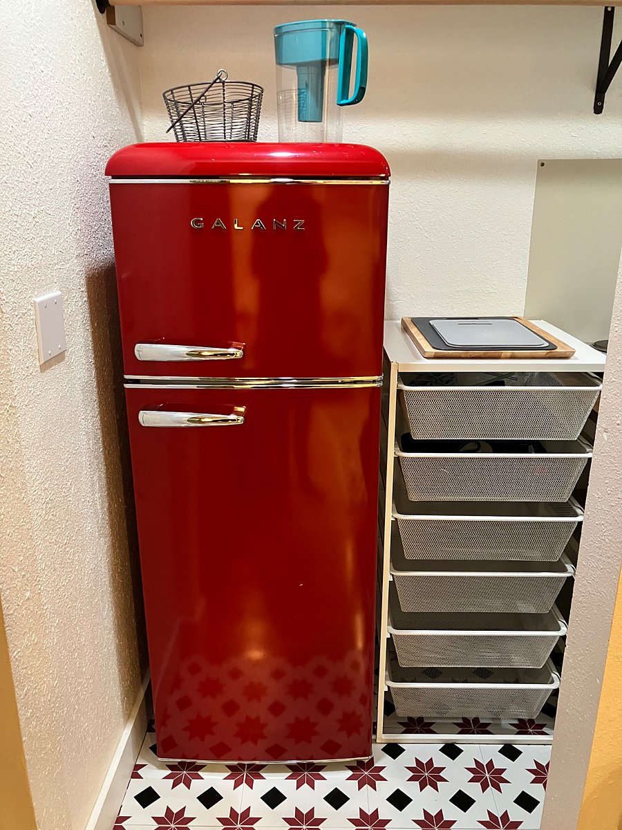 Adorable and well-functioning kitchenette with full fridge and storage shelves.