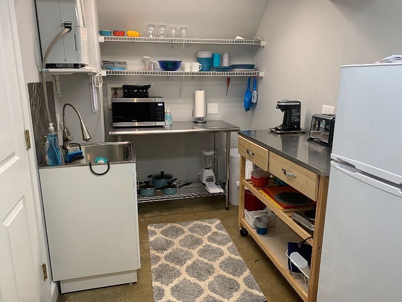 Kitchenette with stainless sink.  Plenty of dish and tableware. Brightly lit.