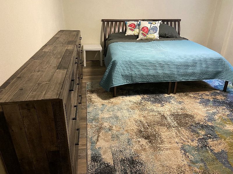 Large bedroom, king-sized bed, two dressers (side-by-side), two end tables, lamp, alarm clock, large closet not shown.