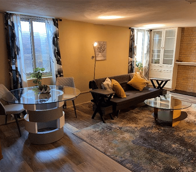 Another view of the living room, which is to the right of the kitchen, showing dining table, which actually has 4 chairs (2 not pictured), and large windows.
