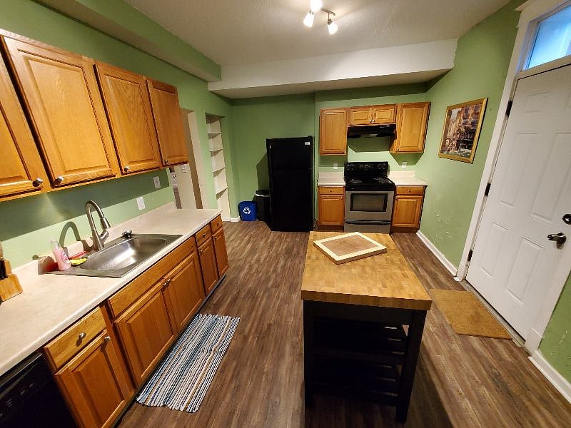 Down the hall is the very spacious kitchen with full size stove, fridge, microwave, and island with a rear entrance leading to the back yard and parking area
