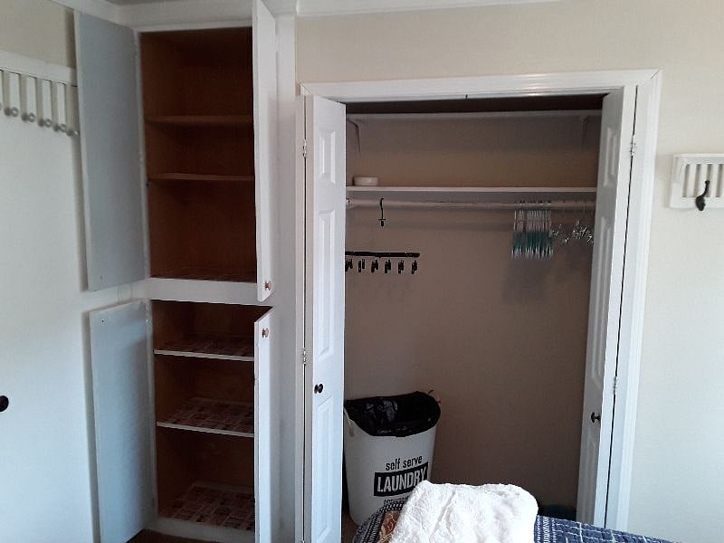 Floor to ceiling cabinets and full closet with large laundry basket, small drying rack and hangers.