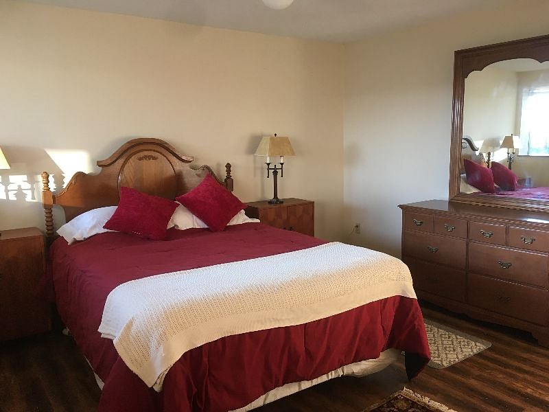 Bedroom with queen bed, dresser and mirror.