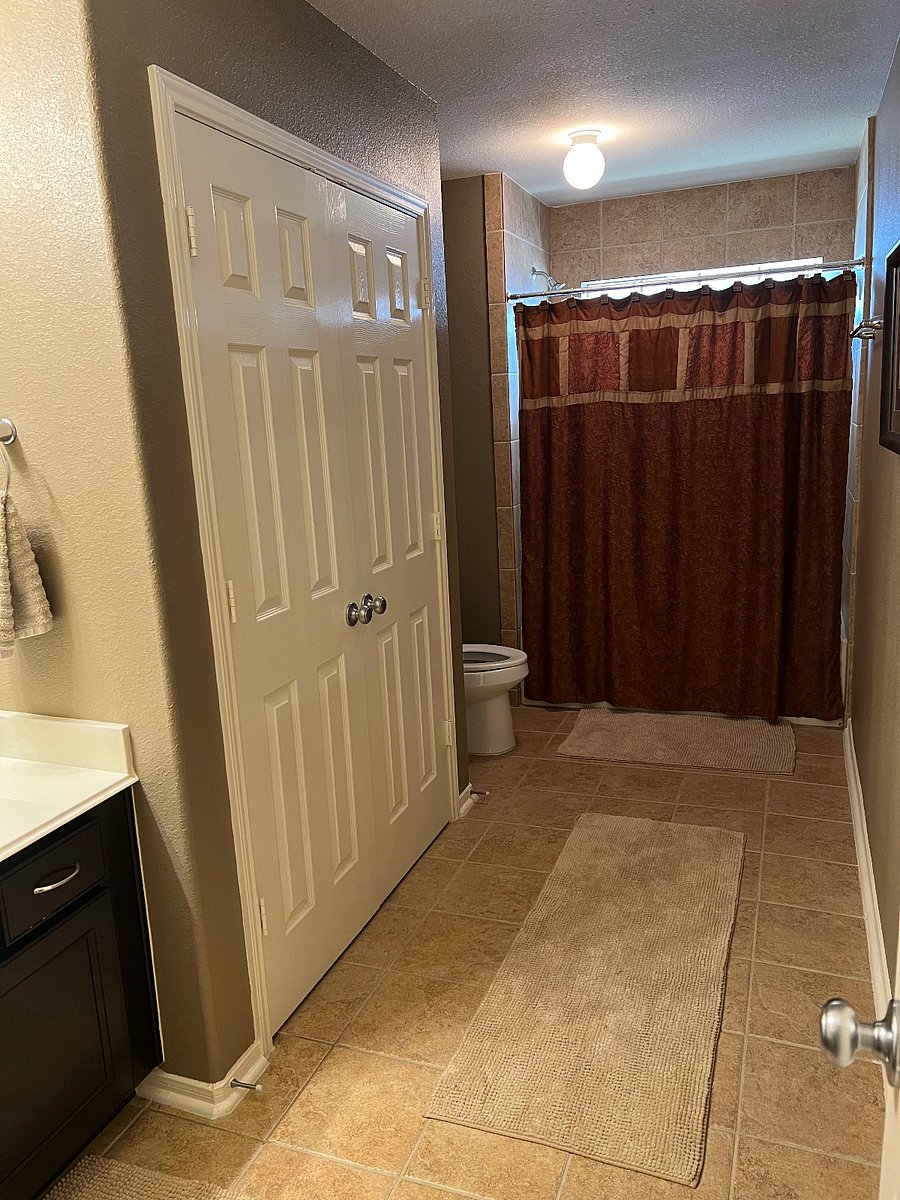 Private bathroom #2 with shower/tub combo, linen closet, and laundry basket.