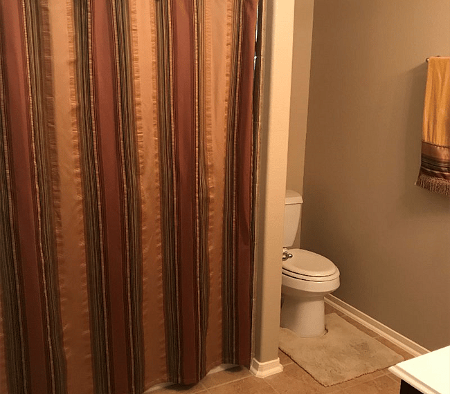 Private bathroom #1 with shower/tub combo, linen closet, and laundry basket.