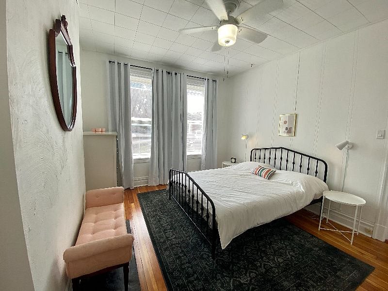 Front bedroom with blackout curtains, ceiling fan, dresser.