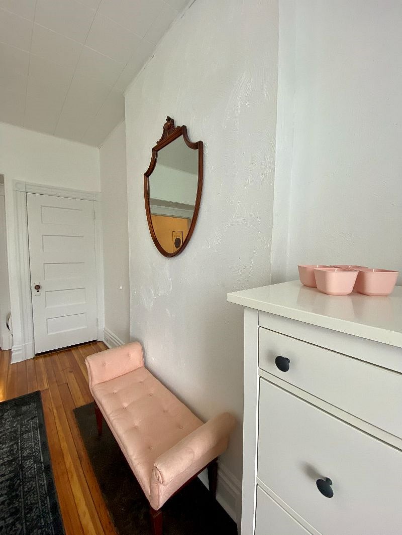 Large dresser, with pink bench and vintage mirror in front bedroom.