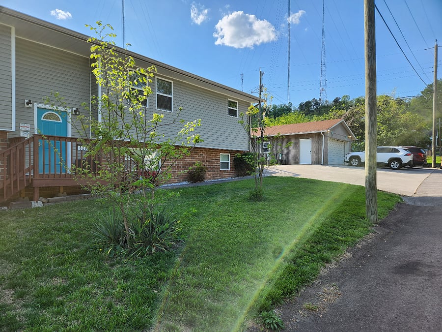 Front of tri-plex and view of front door to shared hallway. Parking to the right.