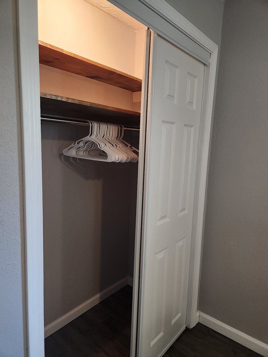 Bedroom 1 closet with provided hangers. Light in the closet.