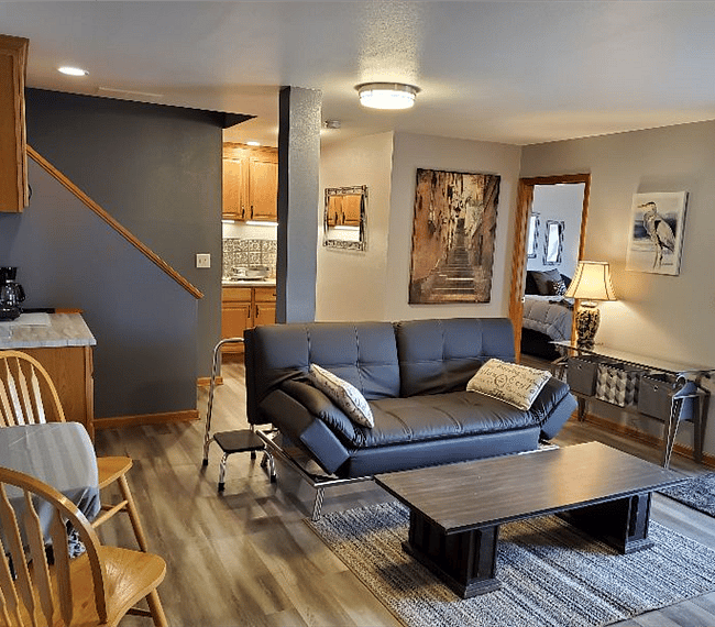 Living room area, leather couch and bedroom doorway to the right. 