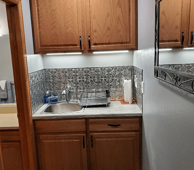 Nicely stocked kitchenette with microwave, air fryer, toaster oven, crock pot, coffee maker, hot plate and pots, pans, utensils.
