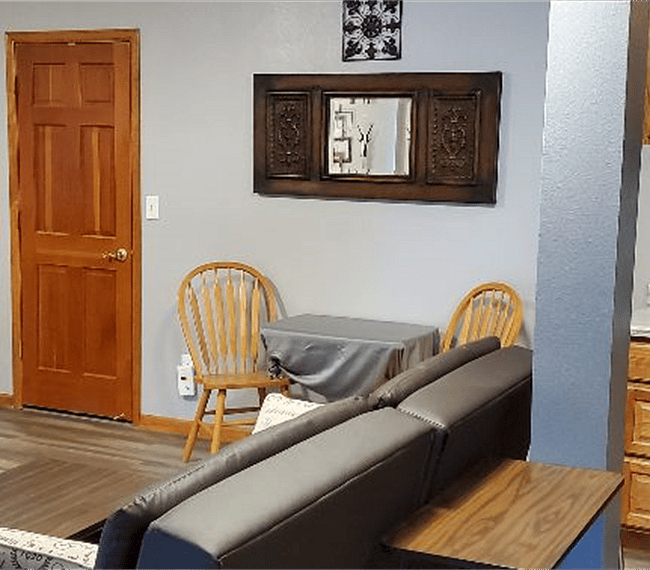 Living room with storage area door on the left kitchenette cabinets and cooking area on the right.