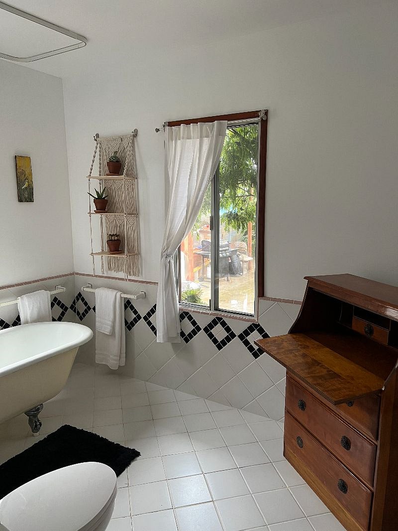 Large bathroom with cast iron tub and shower. Desk cabinet with towels