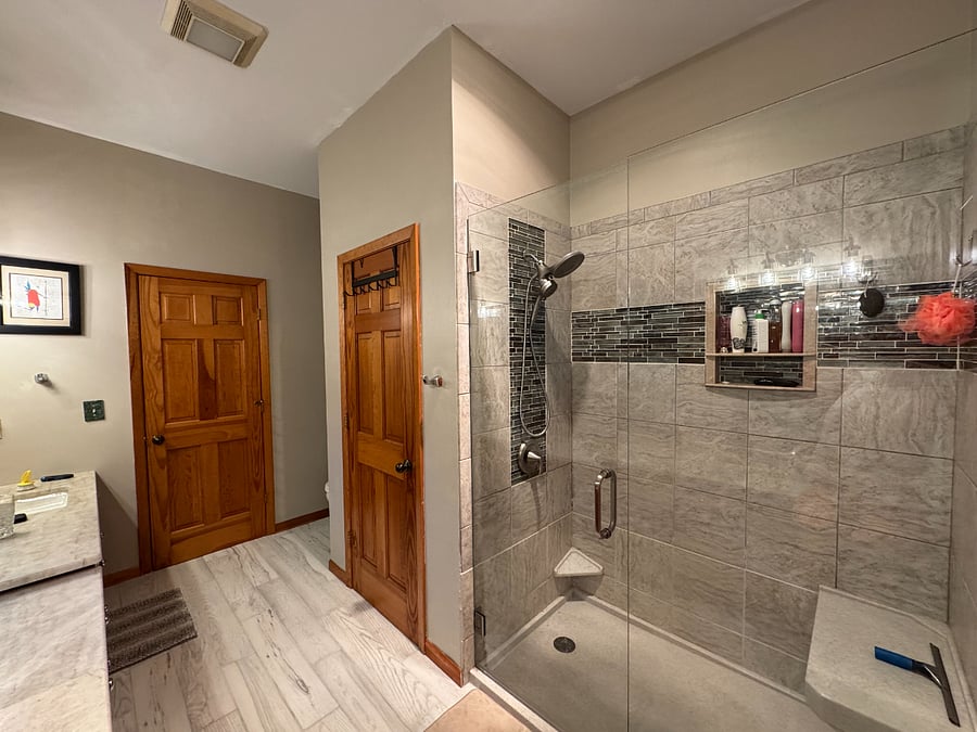 New glassed in tile shower with bench, toe shelf for shaving.  Closet, toilet corner