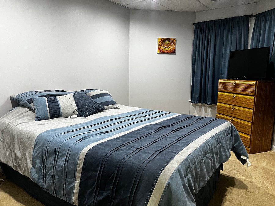 Master bedroom with queen size bed, linens, TV, closet, nightstand, lamp, white noise maker, clock. 