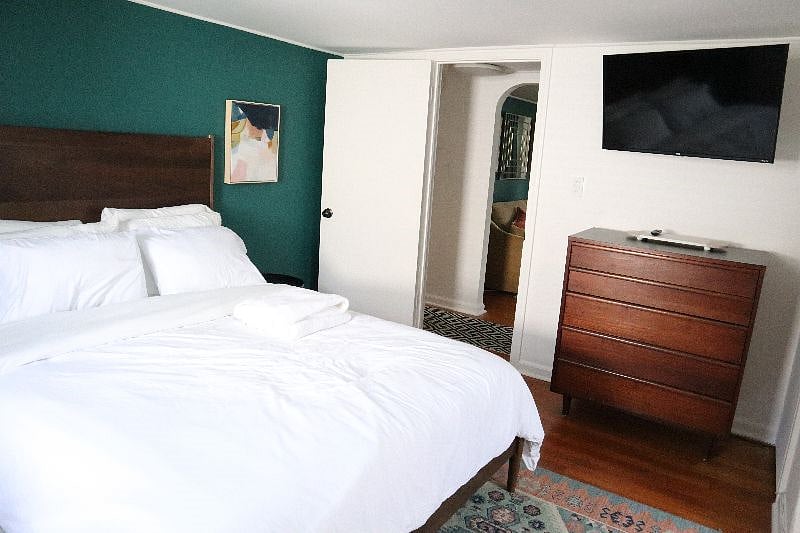 Bedroom with queen size bed, TV, night stands, charging station, air conditioning (summers only), and work area.