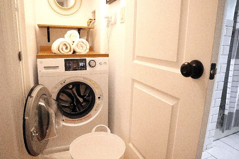 Laundry closet includes a washer/dryer combo, folding station, clothing rod with hangers, and starter laundry detergent.