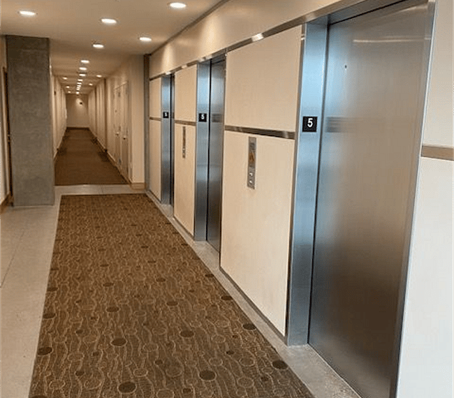 Three elevators service the condominium residents, so one is sure to be along shortly. The unit is just down the corridor a bit, on the left. The trash chute room is just around the corner going the other direction.