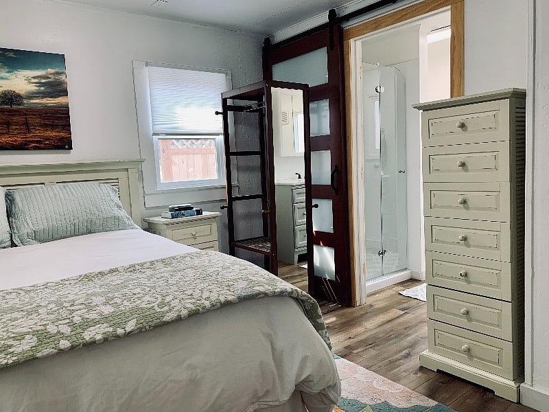 Bedroom with armoire and standing closet, tv, and blackout curtains.