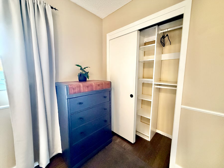 Primary bedroom chest of drawers and closet with organizer.