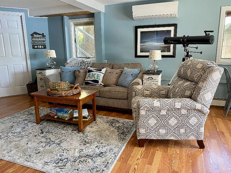deck level family room with big screen tv, gas bot belly stove, sliders to the deck and a beautiful view of the lake